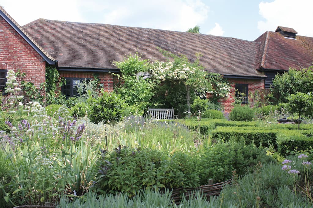 Garden design including rose arch, bench, topiary and planting