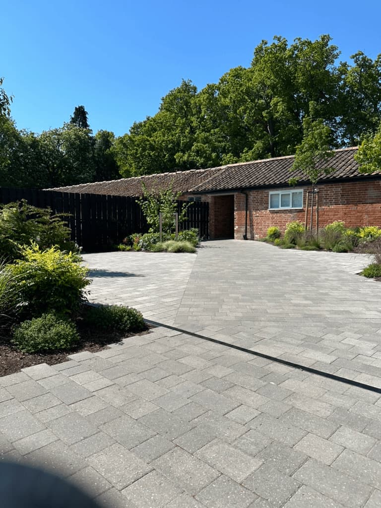 A view across a public walkway to converted farm buildings with planting either side