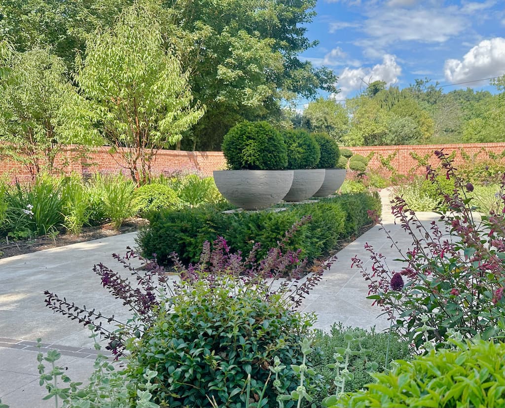 A Walled Garden with a stylish focal point of ball shaped topiary in pots